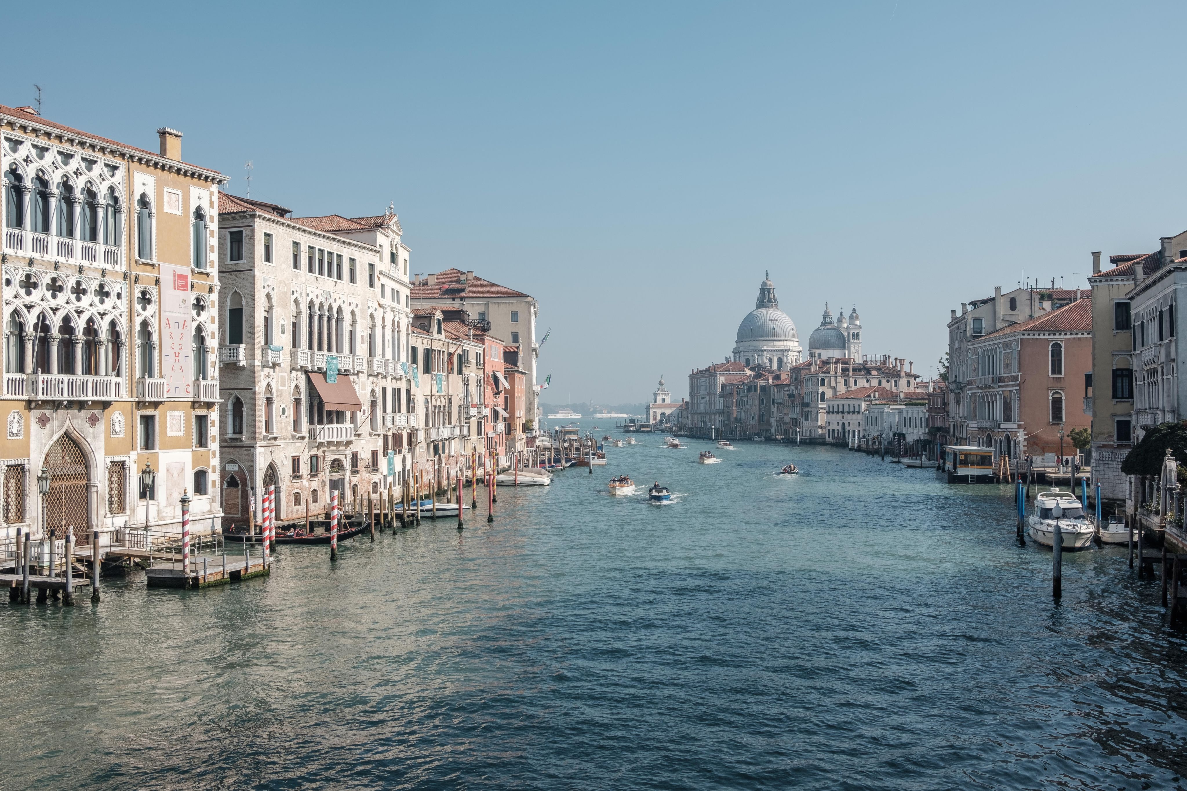 boats running on sea between buildings